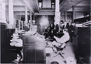 Image of the State Library circa 1910 showing roll-top desk and early electrical wiring.